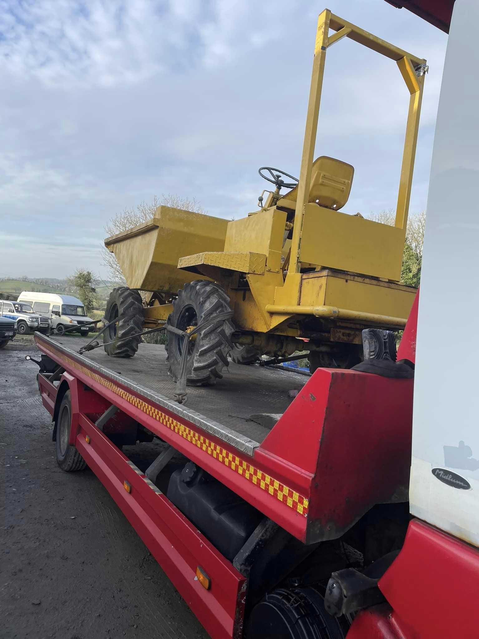 Yellow dumper truck on recovery truck